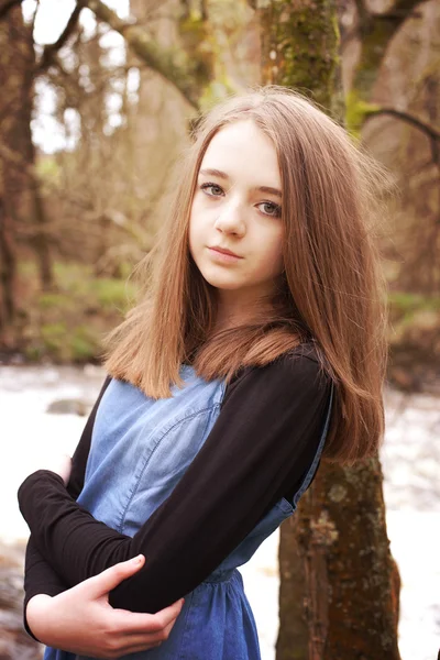 Menina adolescente bonita encostada a uma árvore olhando direto para c — Fotografia de Stock