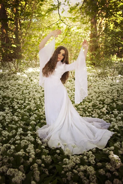 Hermosa mujer vistiendo un vestido blanco largo bailando en un bosque — Foto de Stock