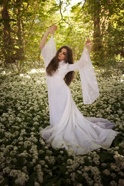 Belle femme portant une longue robe blanche dansant dans une forêt — Photo