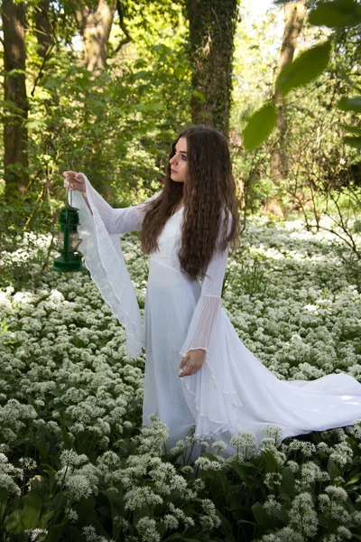 美丽的女人，穿着白色长裙走在森林里一盏灯 — 图库照片