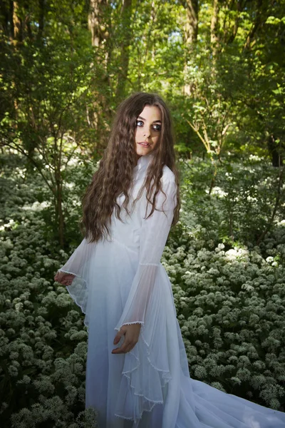 美丽的女人，穿一穿白色长礼服站在森林里 — 图库照片