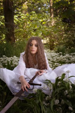 Uzun bir kılıç tutan bir ormandaki güzel genç kadın