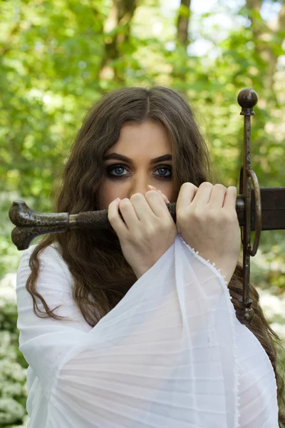 Hermosa joven en un bosque sosteniendo una espada — Foto de Stock