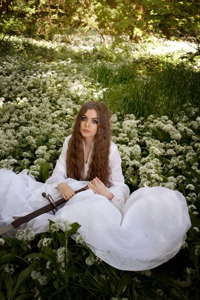 Uzun bir kılıç tutan bir ormandaki güzel genç kadın — Stok fotoğraf