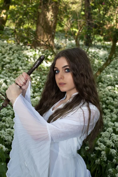 Krásná mladá žena v lese drží meč — Stock fotografie
