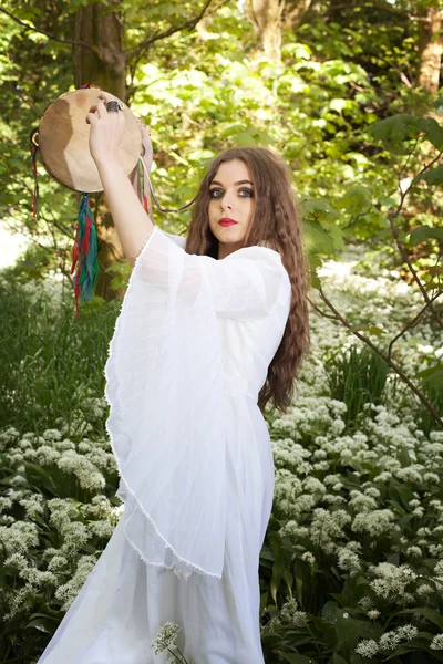 Krásná žena na sobě dlouhé bílé šaty drží tamburína — Stock fotografie