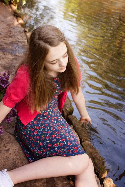 Gyönyörű tizenéves lány ül egy folyó mellett — Stock Fotó