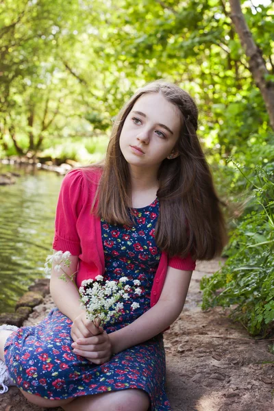 Bela adolescente sentada ao lado de um rio — Fotografia de Stock