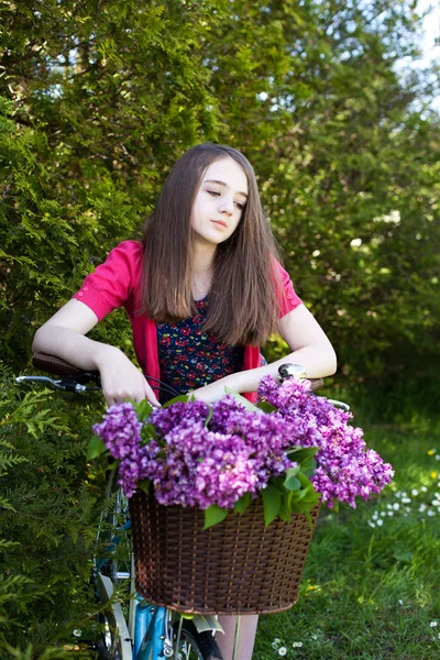 Hermosa adolescente sentada en una bicicleta con una cesta de flores —  Fotos de Stock