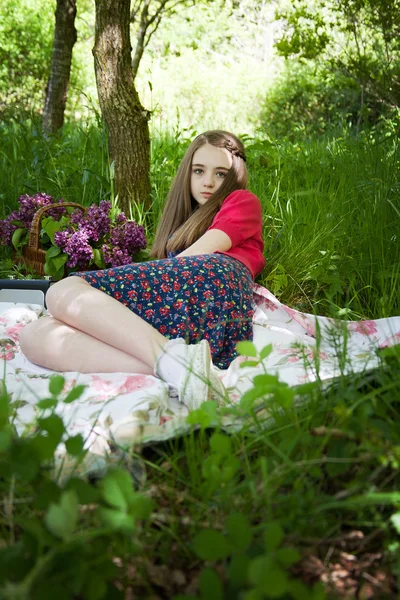 Güzel genç kız üzerinde bir orman bir battaniyeye oturmuş — Stok fotoğraf