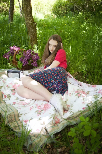 Belle adolescente assise sur une couverture dans les bois — Photo