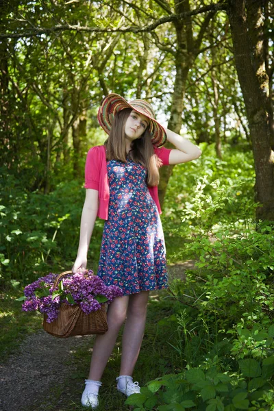 Schöne Teenager-Mädchen zu Fuß in Wäldern mit einem Korb voller Blumen — Stockfoto