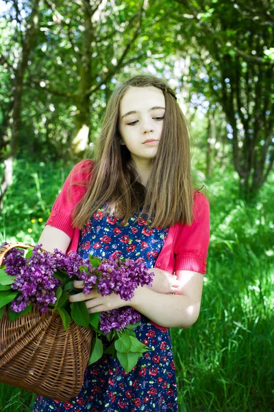 Beautiful young woman holding a basket of flowers — Stock Photo, Image