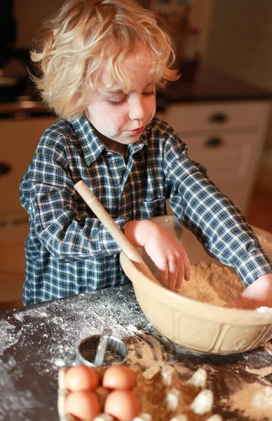 Kleine jongen mengen bloem in een kom — Stockfoto