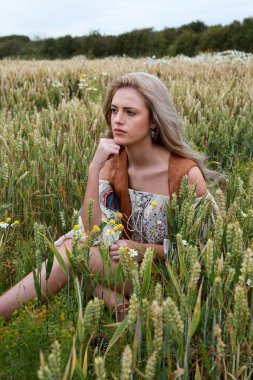 Güzel kız buğday tarlasında oturuyor