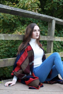 Bir köprü üzerinde oturan uzun kahverengi saçlı güzel genç kadın