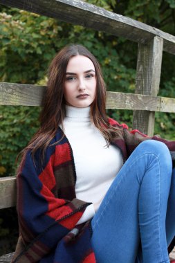 Bir ahşap köprü üzerinde oturan güzel genç kadın