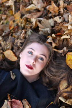 Yaprakların bir yatakta yatarken güzel genç kadın