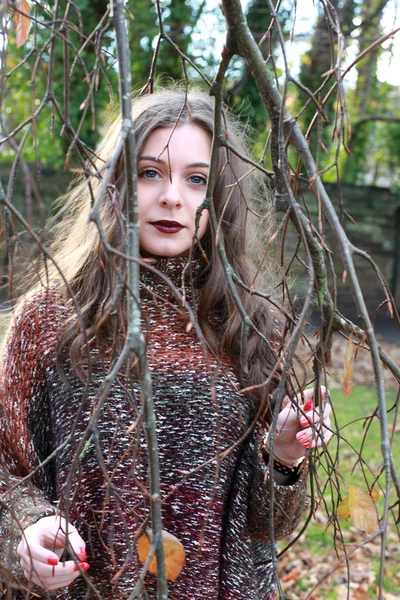 Beautiful young woman looking through branches — Stock Photo, Image