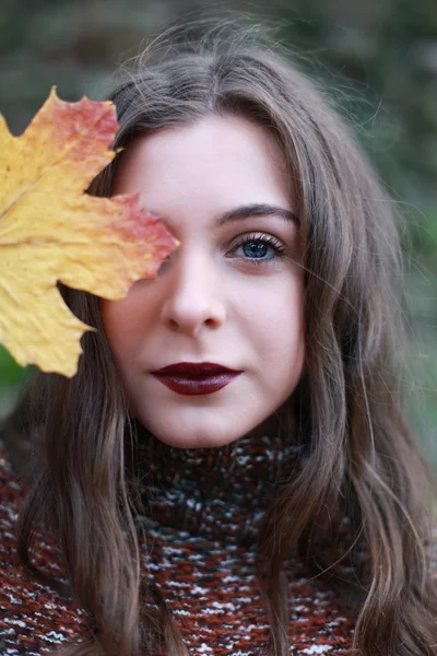 Porträt eines Teenagers, der sich ein goldenes Blatt vor das Gesicht hält — Stockfoto