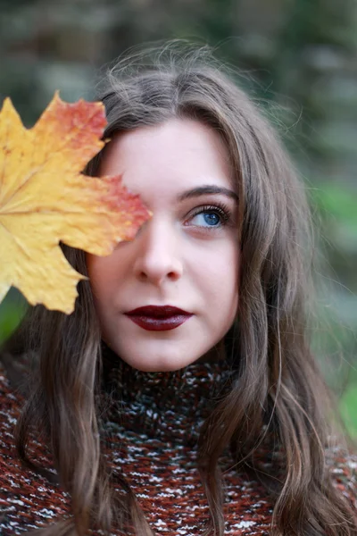 Retrato de una hermosa adolescente sosteniendo una hoja en su cara — Foto de Stock