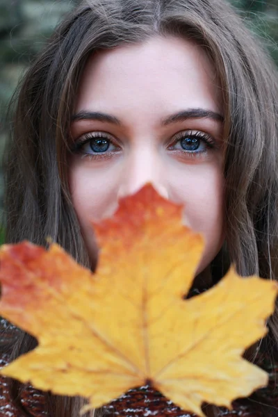 Портрет девочки-подростка, держащей золотой лист на лице — стоковое фото
