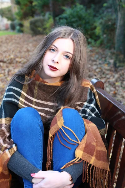Piękna młoda kobieta siedzi na ławce w parku — Zdjęcie stockowe