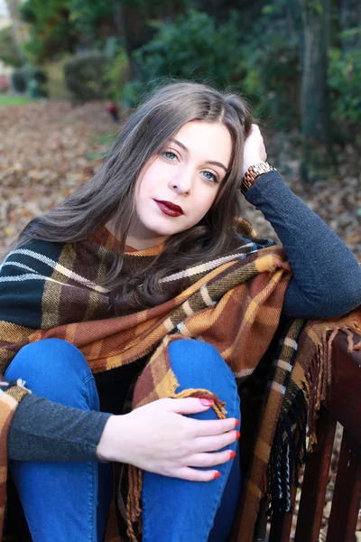 Kaunis teini tyttö istuu puistossa penkillä syksyllä — kuvapankkivalokuva