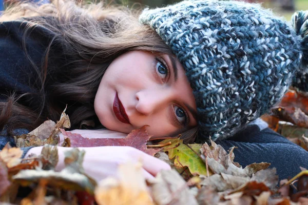 Schöne Teenager-Mädchen liegt auf einem Bett aus bunten Blättern in aut — Stockfoto
