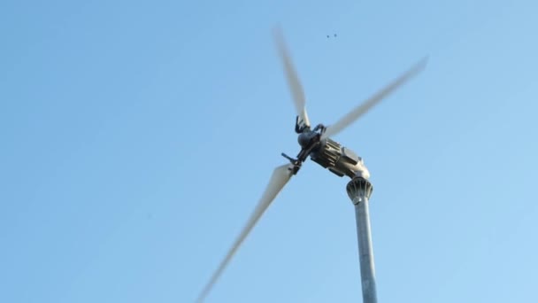 風力発電機は青い空に向かって上昇する風でブレードを回します — ストック動画
