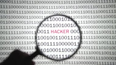 Kırmızı etiketli bir hacker ile ikili kod büyüteçle görüntülenir.