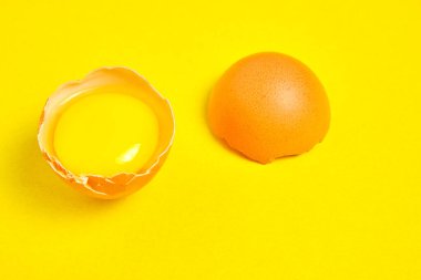 Sarı arka planda yumurta sarısı ile kırılmış tavuk yumurtaları.