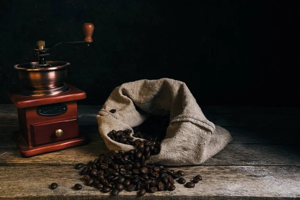 Roasted coffee beans in bag and coffee grinder on an old wooden table