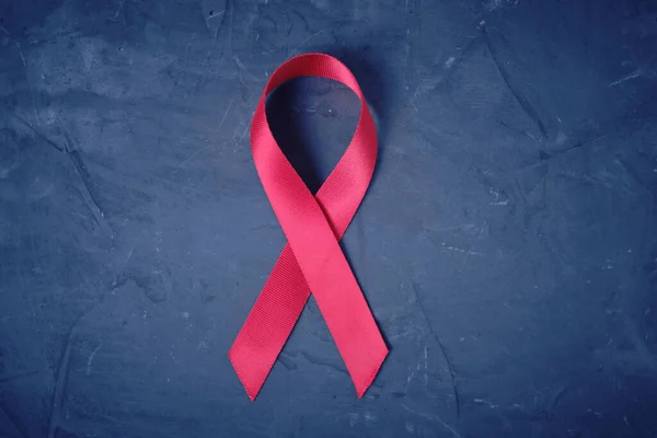 Red ribbon on concrete texture background, symbol of AIDS disease and drug abuse problem