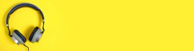 Panorama afişi, sarı arka planda haki rengi kablosuz kulaklık.