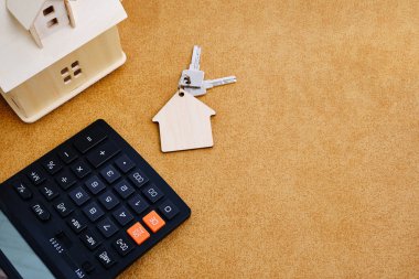 Evde anahtarlarla birlikte hesap makinesi ve anahtarlık. Ev alıp satma, ipotek ve ev ya da daire kiralama kavramı..