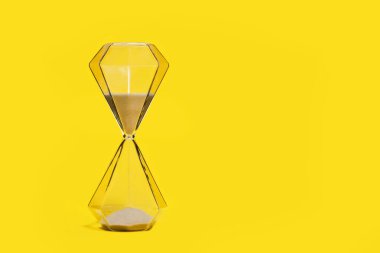 Sarı arka planda kum saati, zaman geçiyor.