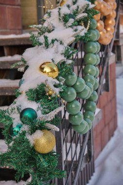 Merdivenlerde yeşil, altın toplar ve çelenklerle süslenmiş Noel ağacı