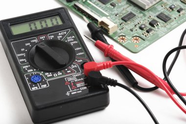 Bilgisayar devre kartının yanındaki perspektif görünümü dijital multimetre. Elektronik donanım sorun giderme ve bakım kavramı