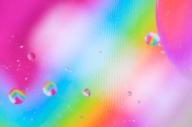 Gökkuşağı renklerinin ve makro ölçekte yüzen sıvı kürelerin yer aldığı parlak soyut arkaplan