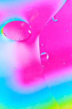 Büyük pembe yağ damlasının sanatsal bileşimi ve mavi arkaplanda küçük yanardöner kabarcıklar.