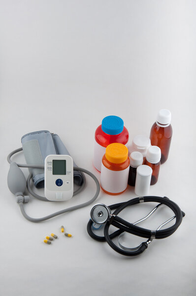Medical tonometer, phonendoscope, pills and drug bottles on white