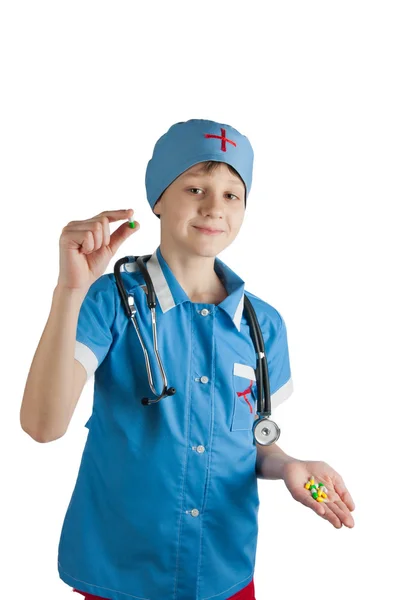 Criança bonito em traje médico e estetoscópio mostrando pílula — Fotografia de Stock