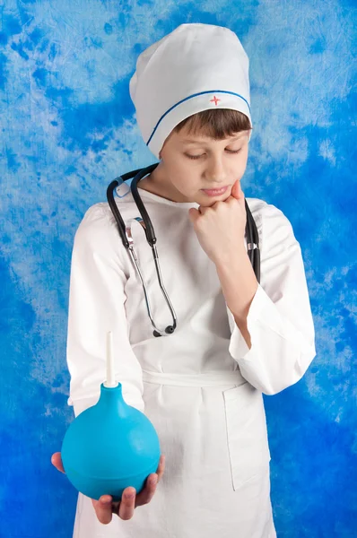 Ragazzo meditativo in costume da medico tenendo clistere — Foto Stock