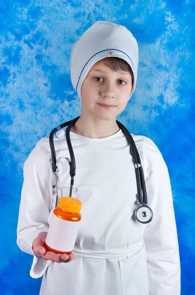 Niño en traje de médico sosteniendo píldoras botella — Foto de Stock