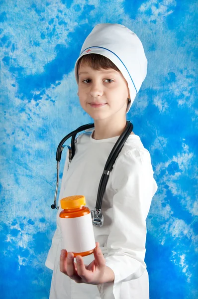 Niño en traje médico celebración botella con pastillas —  Fotos de Stock