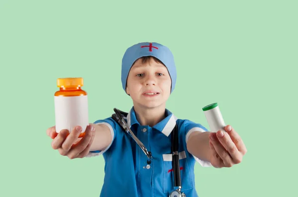 Мальчик в костюме доктора показывает бутылки с таблетками — стоковое фото