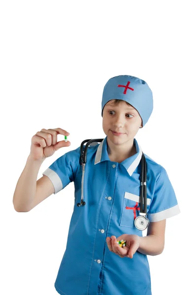 Niño en traje de médico y estetoscopio mirando píldora — Foto de Stock
