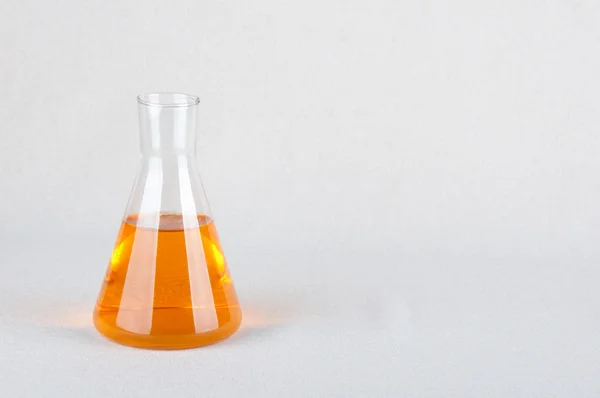 Artículos de vidrio de laboratorio y líquido naranja en el interior — Foto de Stock