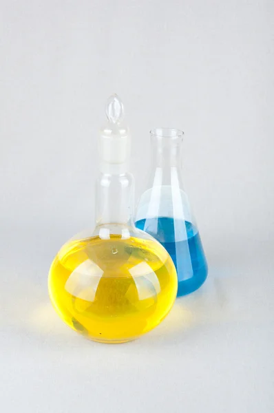 Artículos de vidrio de laboratorio y azul, líquido amarillo en el interior — Foto de Stock